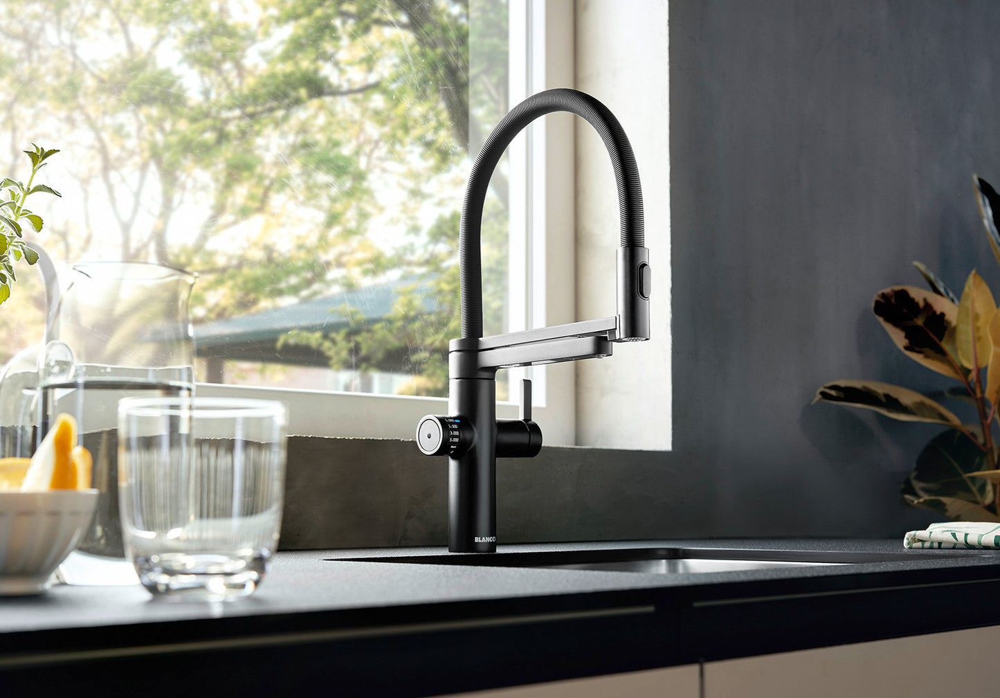 Side view of the BLANCO EVOL-S Pro Filter mixer tap in Black Matt finish, featuring a professional flexible spring spout and separate filtered water outlet on a modern kitchen island.