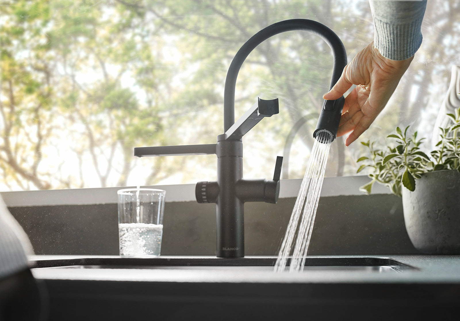 Using the pull-down spray head of the Black Matt BLANCO EVOL-S Pro for rinsing, while the secondary spout provides a steady flow of filtered drinking water.