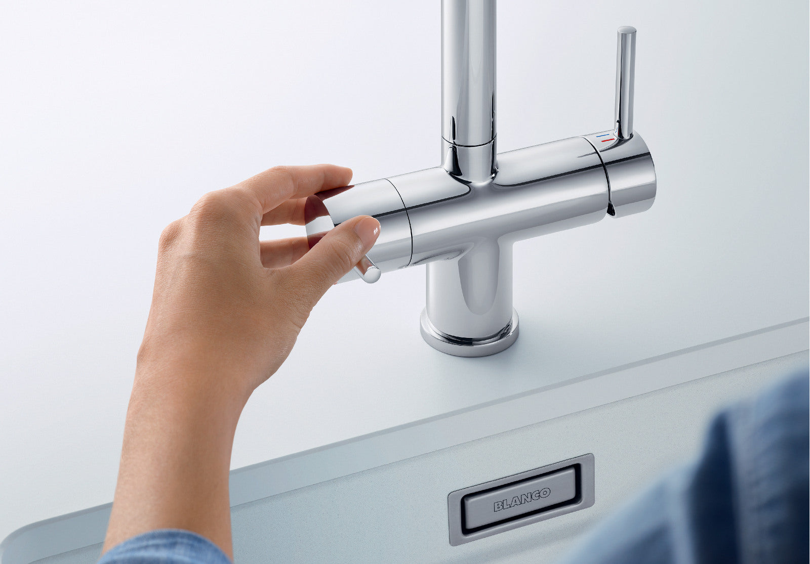 Detailed view of the BLANCO Fontas-S II Filter Mixer, focusing on a hand engaging the dedicated filtered water lever on the left. The separate internal waterways prevent filtered and standard water from mixing, optimizing hygiene for purified drinking