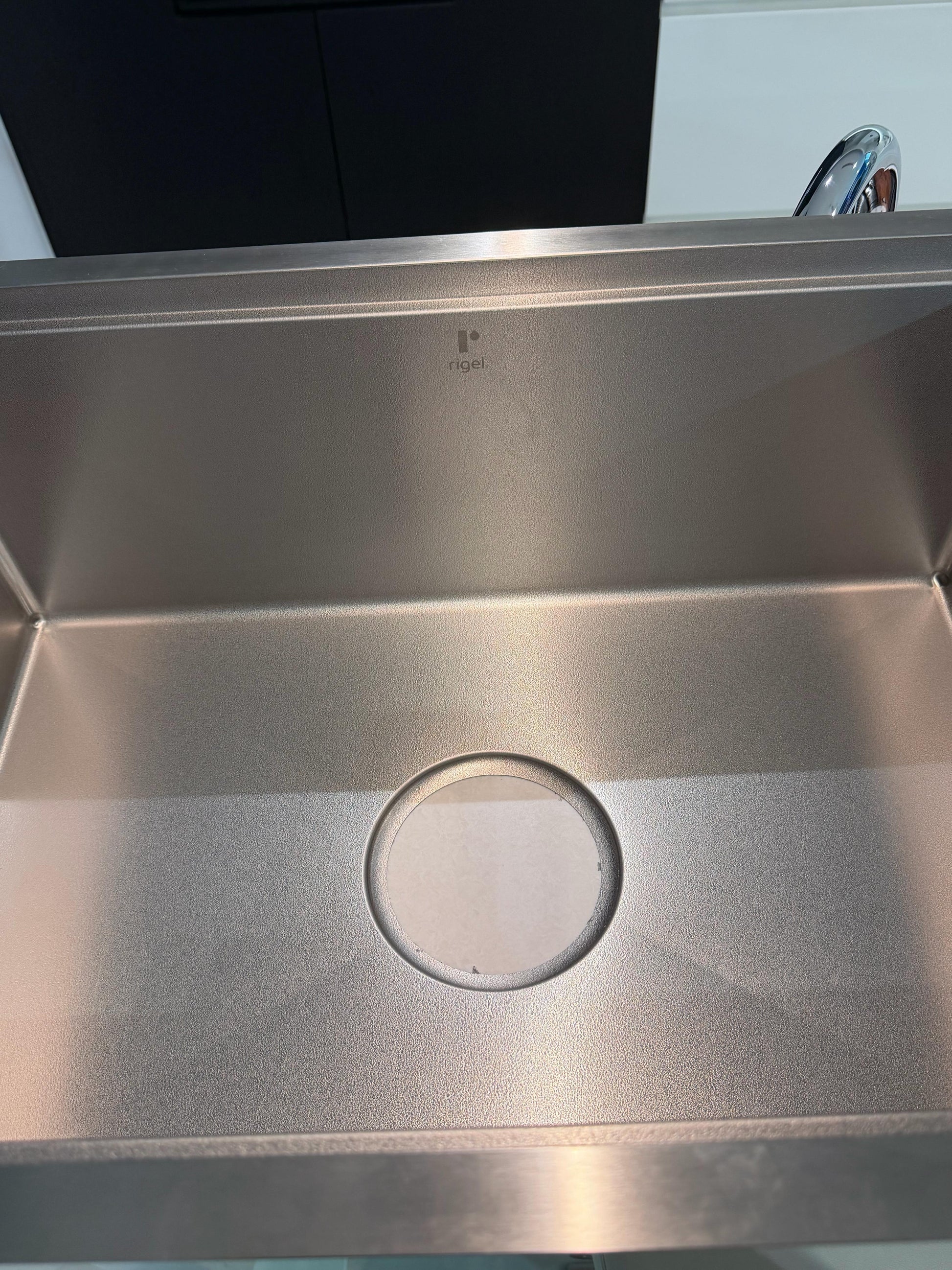 Stainless steel kitchen sink with a Rigel brand log, close up view