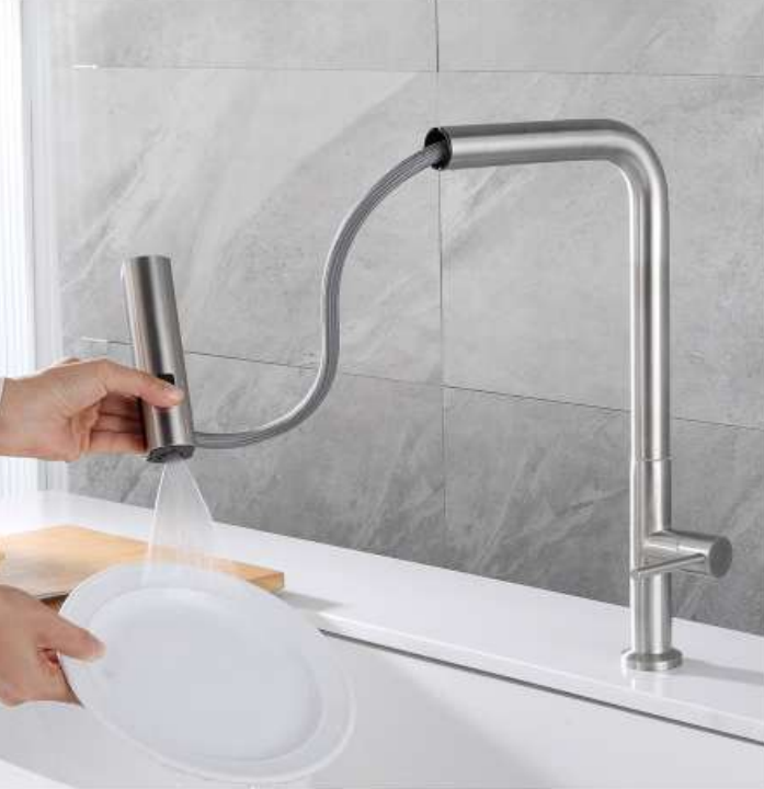 Action shot of the ZAFFIRO PT-514SS-T Matt SUS304 kitchen tap with its pull-out spray head extended, being used to rinse a white ceramic plate over a sink.